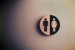 A circular sign with the traditional symbols for men's and women's restrooms