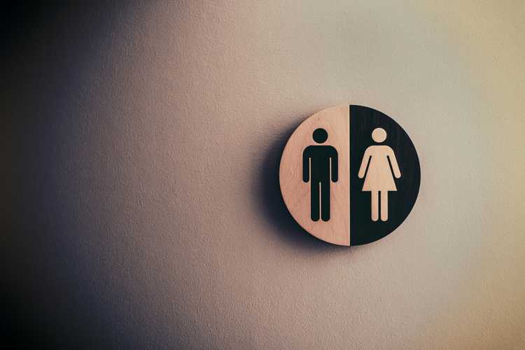 A circular sign with the traditional symbols for men's and women's restrooms